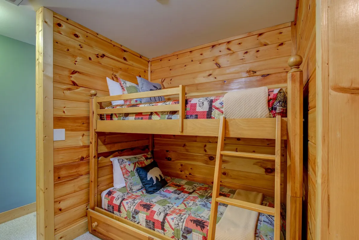A playful bunk room with two sturdy bunk beds, colorful bedding, and wooden walls. The space is lively yet comfortable, perfect for children or friends to enjoy restful, memorable stays.