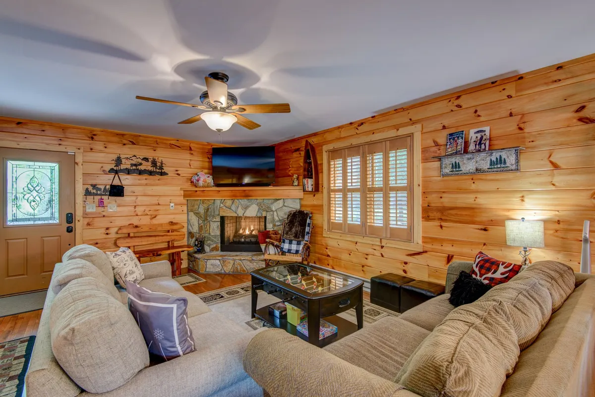 The living area features a cozy fireplace, a comfortable sofa, a coffee table, and large window views. The atmosphere feels warm and welcoming—ideal for relaxing with a hot drink after outdoor activities.