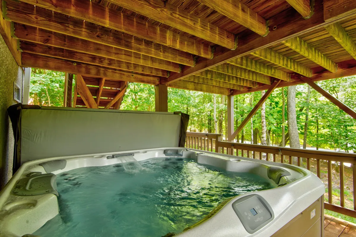 This image shows an inviting hot tub set against wooden beams, with lush greenery visible just outside. The scene is tranquil and exudes relaxation, perfect for unwinding after a day of adventure.
